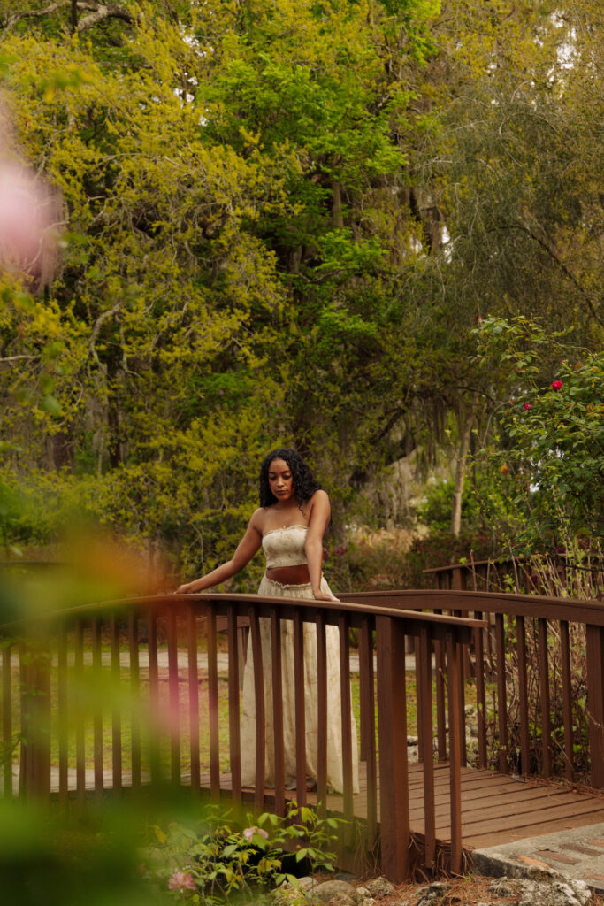 Woman standing on a wooden bridge surrounded by greenery during her Sholom Park branding session