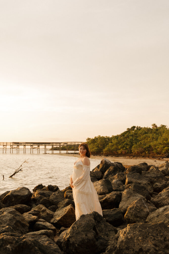 Woman standing among the rocks near the water at Fort Island Gulf Beach during golden hour