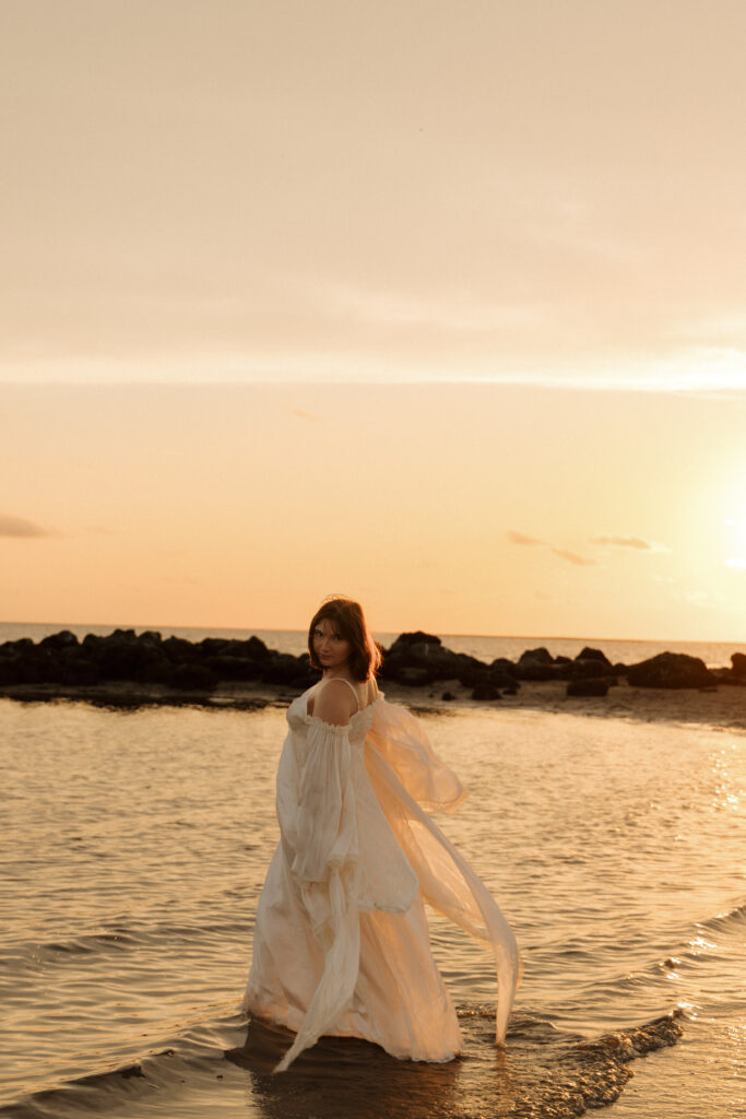 Woman standing in the shallow water at sunset during her Fort Island Gulf Beach portrait session