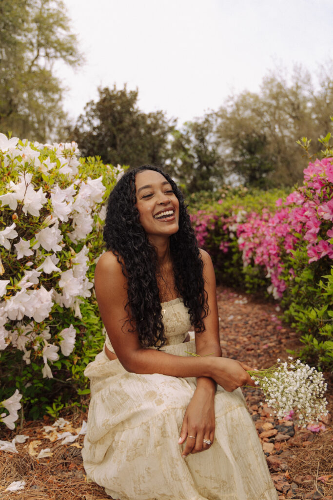 Woman smiling among pink and white azaleas during her personal branding session at Sholom Park