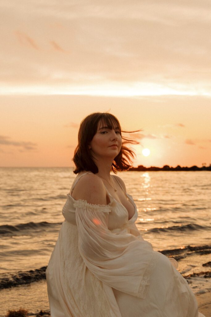 Woman posing near the shoreline with the sunset behind her at Fort Island Gulf Beach