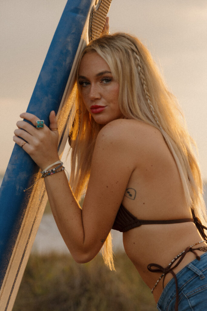 Woman carrying a Wavestorm surfboard during a surfer inspired beach portrait session