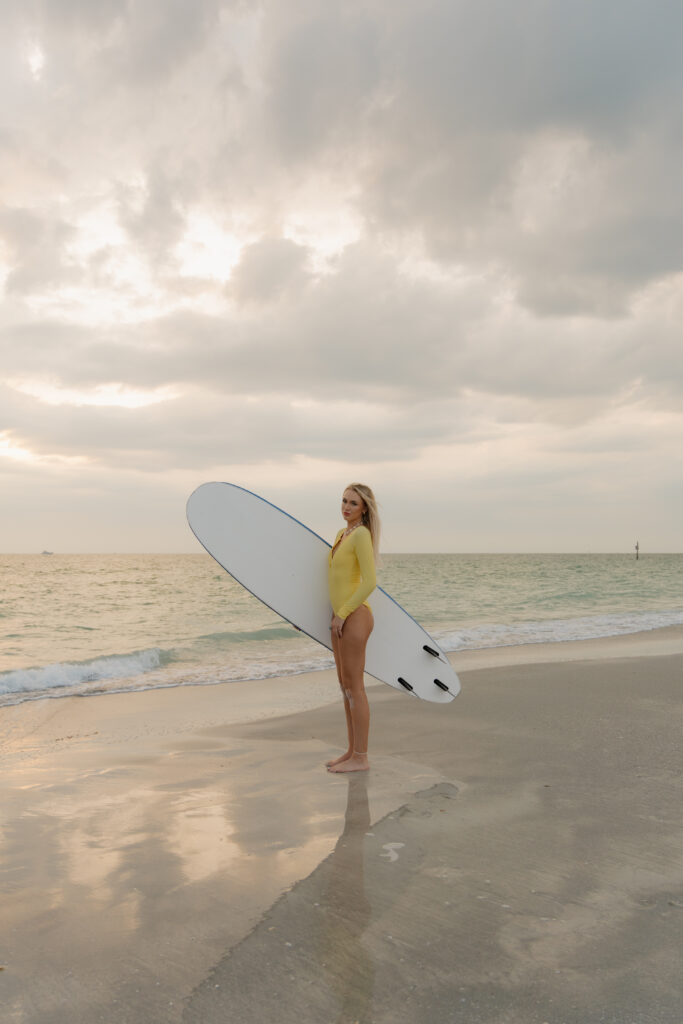 Woman holding a Wavestorm surfboard along the shoreline at Sand Key Park in Clearwater Florida