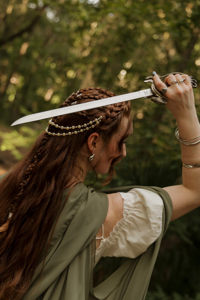Woman holding a sword above her head during a medieval inspired portrait session in Ocala Florida