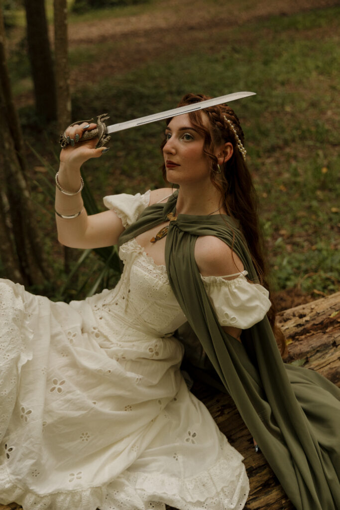 Woman under a sheer veil holding an ornate sword during a painterly medieval inspired portrait session