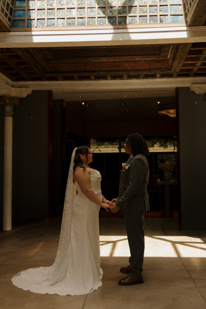 Bride and groom holding hands beneath the skylight at the Morse Museum in Winter Park
