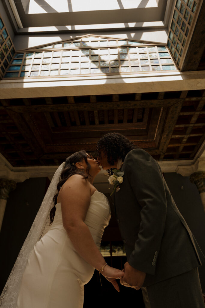 Bride and groom kissing beneath the stained glass ceiling at the Morse Museum