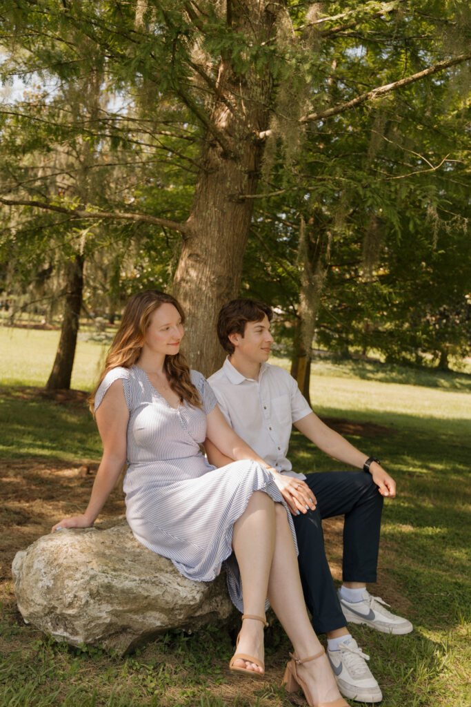 Couple sitting together on a large rock beneath the trees at Sholom Park