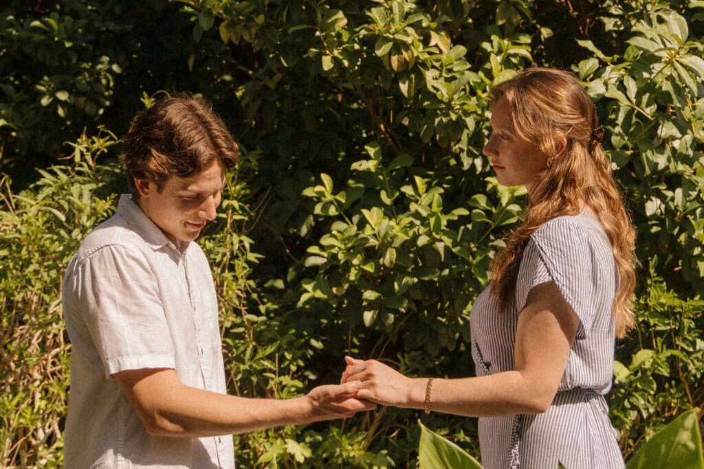 Engaged couple holding hands surrounded by greenery during their Sholom Park engagement session
