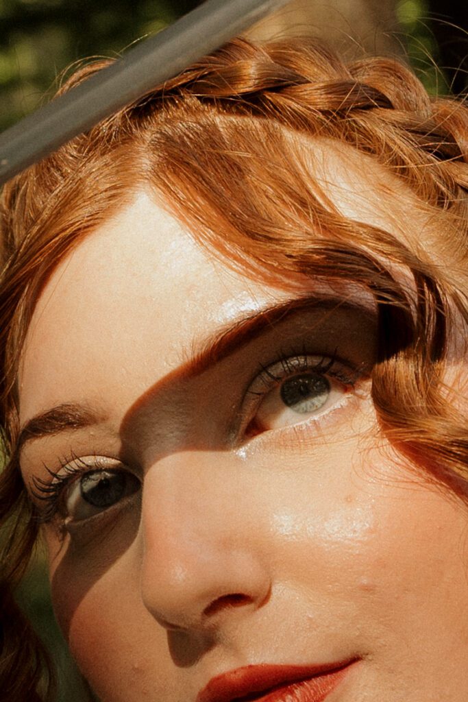 Close up portrait of a red haired woman with braided medieval inspired hair and dramatic makeup